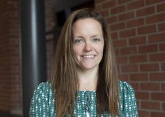 Katelynn Purinton in green shirt stands in front of brick wall.