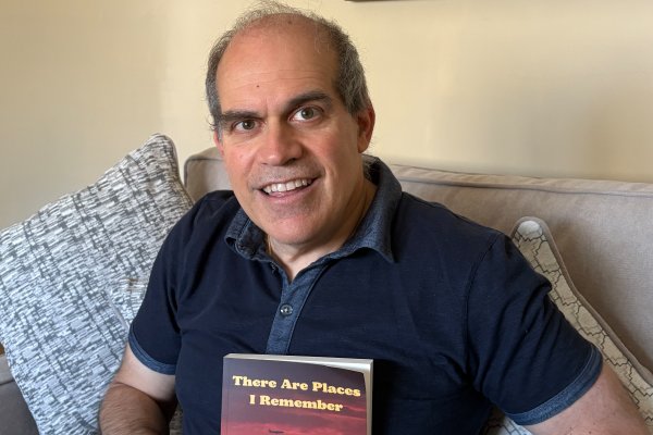 Mike Dileo '89 in blue polo shirt, holds a copy of his book - "There are Places I Remember."