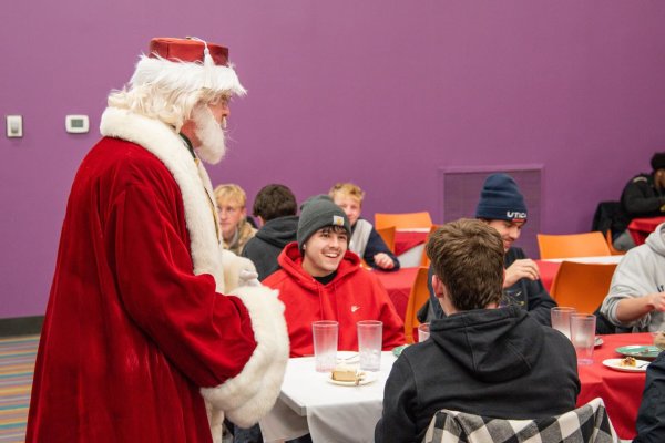 Santa Claus visits with students at the 2025 Holiday Dinner.